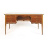 A 1950/60's walnut and crossbanded bow-fronted desk with an arrangement of six drawers over a