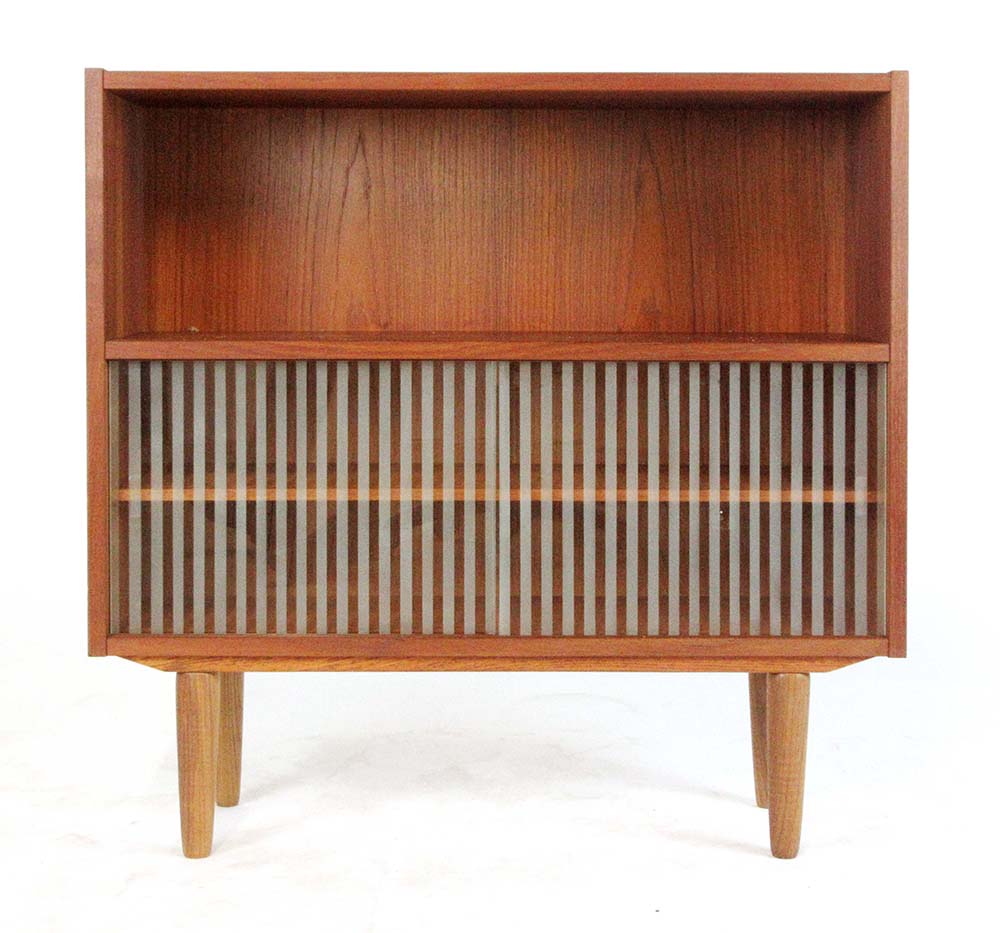 A 1970's teak bookcase, the bottom two shelves enclosed by a pair of striped glass doors,