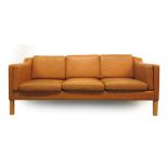 A 1970's tan leather three seater sofa on beech legs,