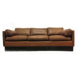 A 1970's brown three seater sofa on a black plinth base