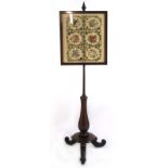 A Victorian rosewood and mahogany pole screen with floral needle work panel over a fluted stylised