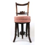 An early 19th century walnut adjustable music/correction stool with floral pink upholstery on