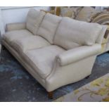 SOFA, three seater, in beige fabric on square supports with castors, 213cm L.