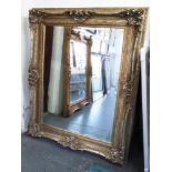 MIRROR, Louis XV style, having an ornate silver gilt swept frame with bevelled plate,