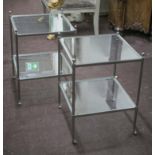 LAMP TABLES, a pair steel with two square glass tiers on castors, 60cm H x 44cm W.