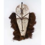 FANG FACE MASK, Gabon carved and whitened wood with rafia fringe, approx 61cm H x 24cm max.