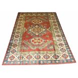 KAZAK CARPET, 305cm x 215cm, geometric medallions on a ruby field within corresponding borders.