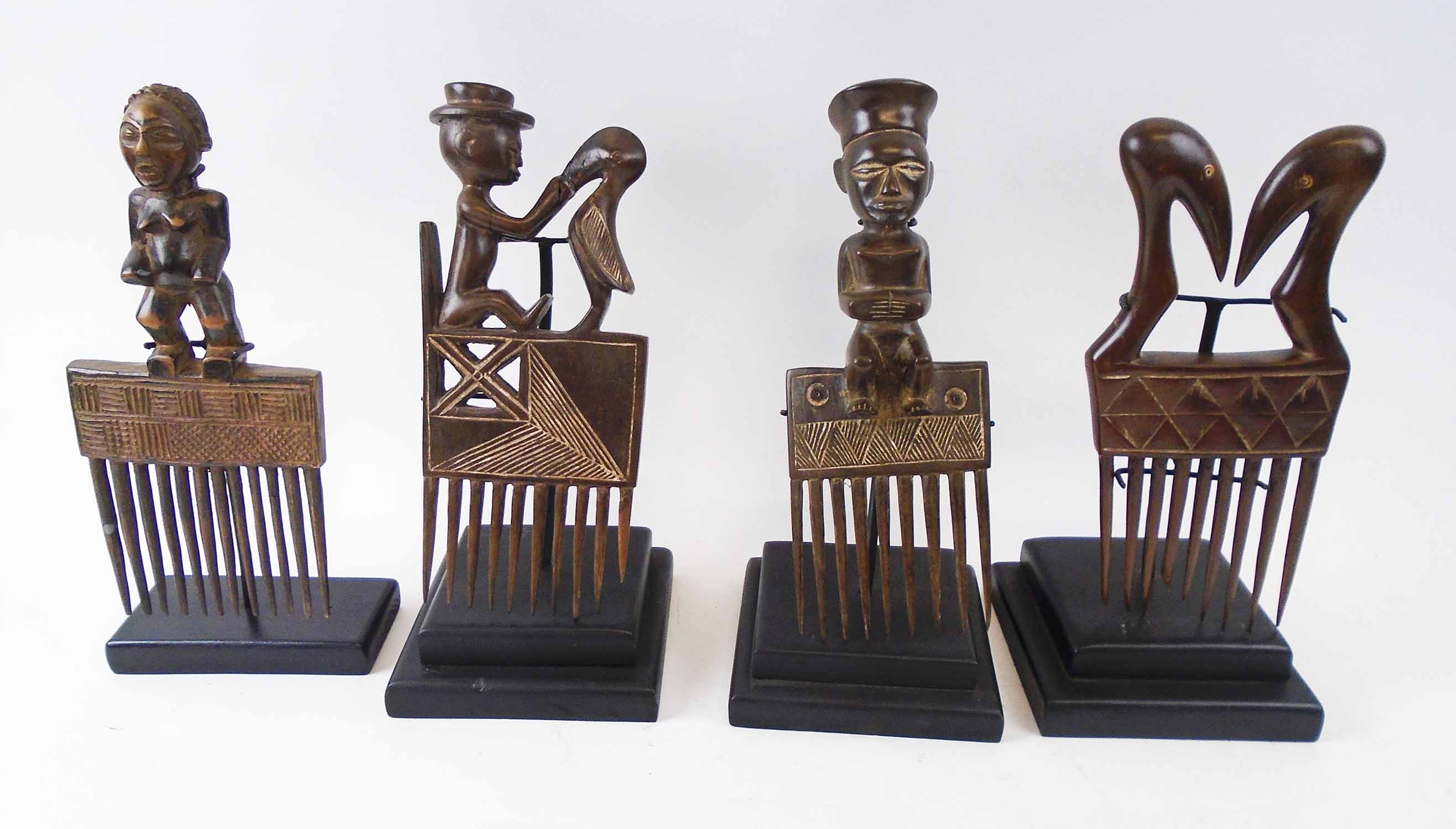 FOUR VARIOUS DECORATIVE COMBS, Cote d'Ivoire, carved wood, each approx. 27cm H, plus display stands.