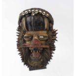 NIGILI FETISH FACE MASK, carved and painted wood, ornamented with cowry shells, spiked dowels,