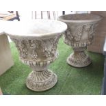 URNS, a pair, in reconstituted stone, with floral swags and faces of Pan decoration, 56cm H.