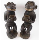 BAULE MONKIES, a pair, each in crouching pose and holding a bowl, carved wood, 56cm H.