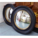 BUTLERS MIRRORS, a pair, ebonised frames with gilt accents, 74cm diam.