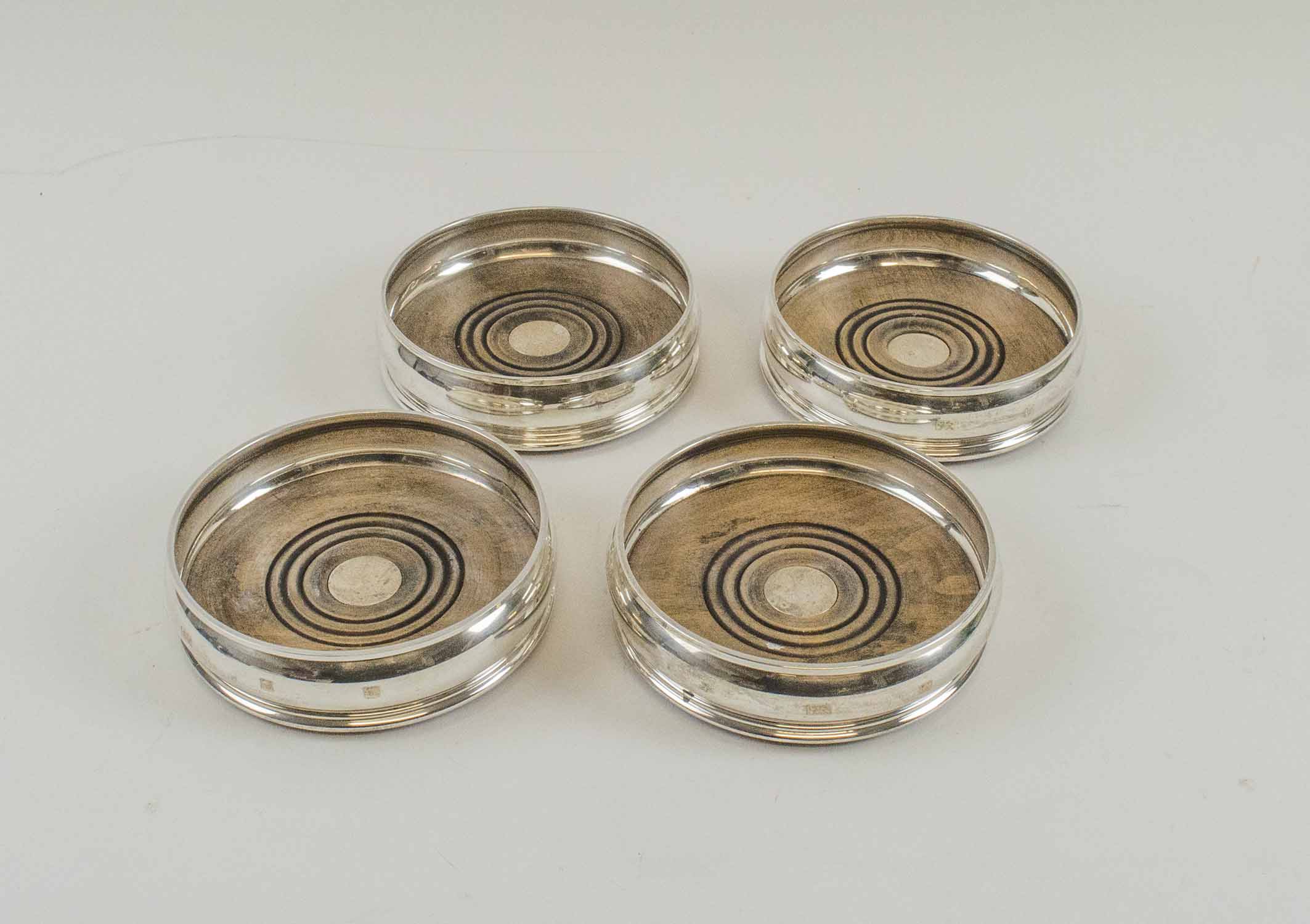 SILVER WINE COASTERS, a set of four, turned wooden bases, London 1994, makers mark MCH, 13cm diam.