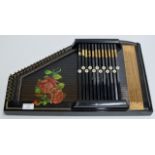AN OLD EBONY FINISHED ZITHER INSTRUMENT WITH ROSE DECORATION
