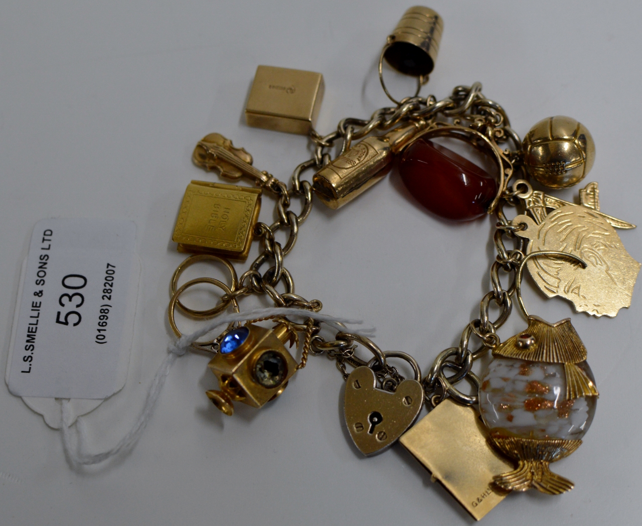 13 VARIOUS 9 CARAT GOLD CHARMS INCLUDING A MASONIC CHARM, MOUNTED ON A STERLING SILVER GILT BRACELET