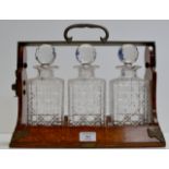 A BETJEMANN OAK 3 DIVISION TANTALUS WITH A SET OF 3 CUT CRYSTAL DECANTERS THERE IN