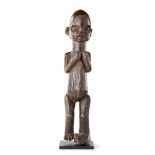 SUKU FIGURE carved wood, shown clasping hands up towards the chest, dark patina, mounted 44.5cm high
