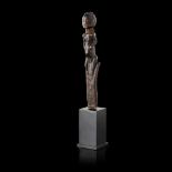 LUBA STAFF FINIAL carved wood, panel with bands of hatching surmounted by a seated female figure