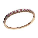 A ruby and diamond set hinged bangleclaw set with a row of alternating round cut diamonds and