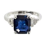 An Art Deco style sapphire and diamond set ringclaw set with a trap cut sapphire, flanked to