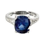 A sapphire and diamond set ringclaw set with a cushion cut sapphire, the tapering shoulders each set