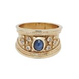 A sapphire and diamond ringof broad design, set with and oval sapphire cabochon, each shoulder set