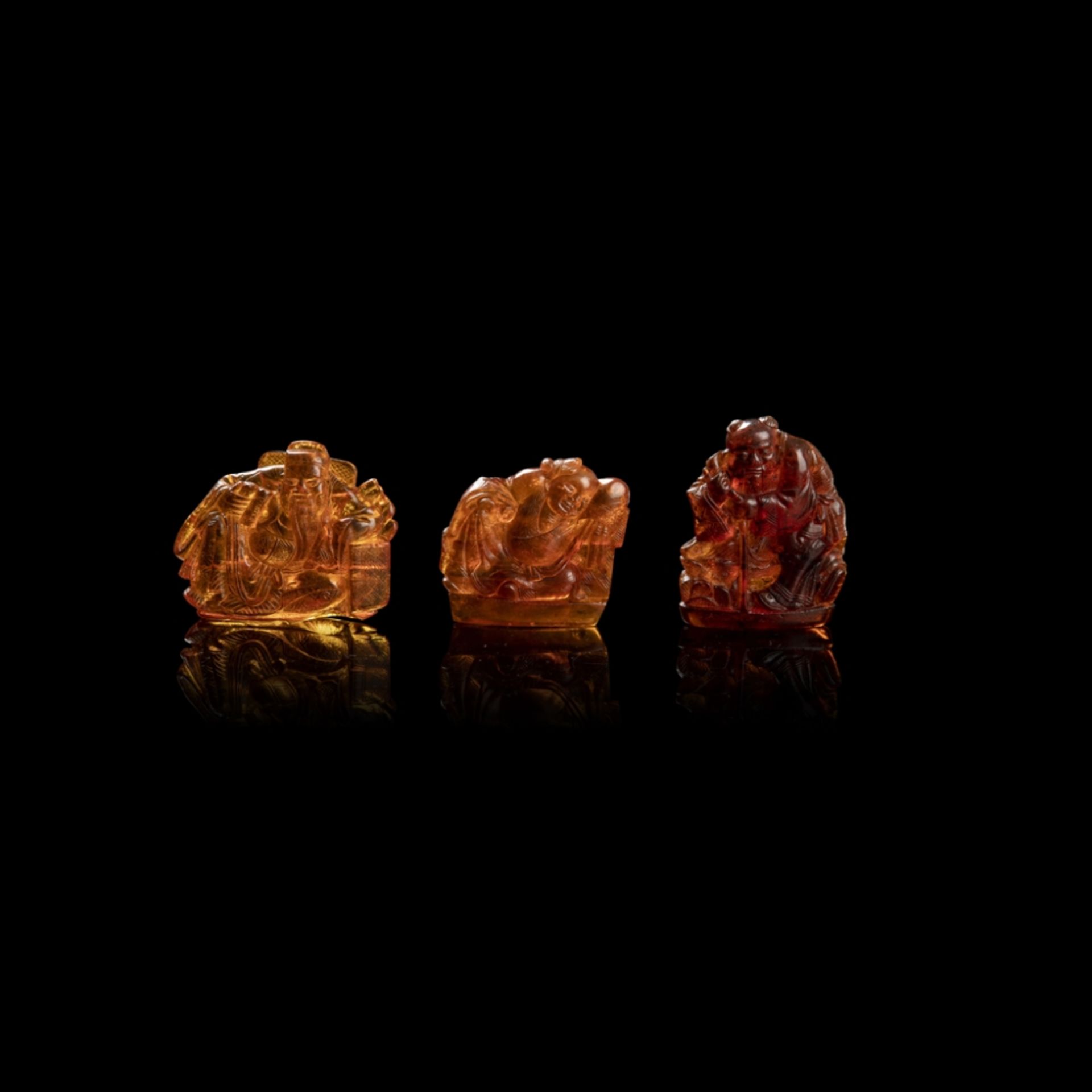 THREE AMBER 'IMMORTALS' CARVINGSQING DYNASTY, 19TH CENTURY depicting three of the 'Eight