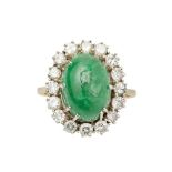 An emerald and diamond set cluster ringclaw set with an oval emerald cabochon, in a single border of