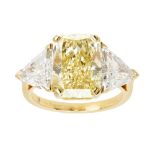 A fancy yellow and colourless three stone diamond ring, De Beersclaw set with a radiant cut fancy