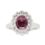 A ruby and diamond cluster ringmillegrain set with an oval cut ruby, in a single border of small