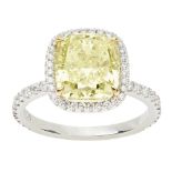 A yellow and colourless diamond set ringclaw set with a cushion cut fancy light yellow diamond, in a