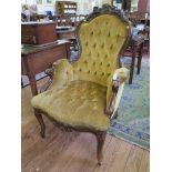 A Victorian style carved wood button back armchair, with foliate scroll decoration