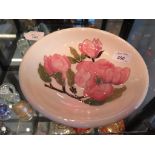 A Moorcroft plate, the pink floral design on a cream ground impressed mark and painted initials,