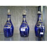 A set of three Bristol blue glass decanters painted with wine labels in gilt, later white metal