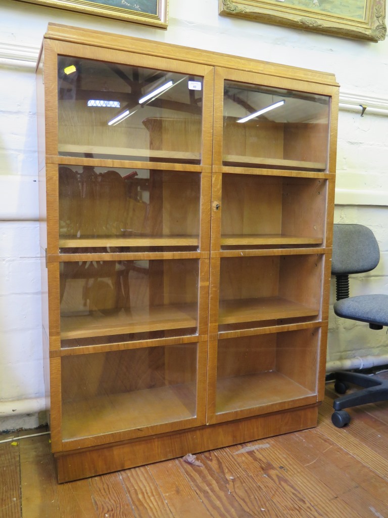 A 1930s oak and walnut banded bookcase, with moulded top and twin glazed doors on a plinth base,