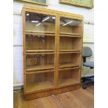 A 1930s oak and walnut banded bookcase, with moulded top and twin glazed doors on a plinth base,
