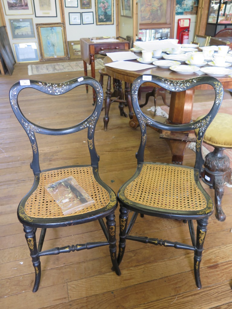 A pair of black lacquered Victorian balloon back chairs, with mother of pearl inlay, cane seat and
