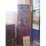 A reproduction mahogany corner cabinet with glazed door and oval panel door