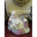 A Chinese Buddhist figure playing with two children, eight character impressed mark 21cm high