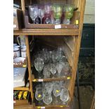 A large collection of drinking glasses, including some coloured (three trays)