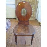 A late George III mahogany hall chair, the oval back with painted crest over a solid seat and turned