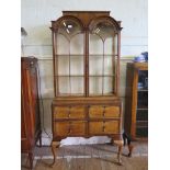 A Queen Anne style crrossbanded walnut display cabinet, the arched glazed doors over four short