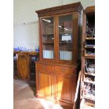 An Edwardian stained beech bookcase cabinet, the moulded cornice and scroll frieze over a pair of