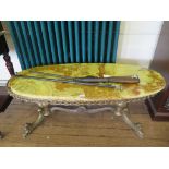 An Onyx and brass coffee table, the oval top on twin baluster supports on scroll legs and castors,