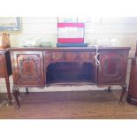 A 1920s mahogany sideboard by Maple & Co, the central drawer and open shelf flanked by foliate