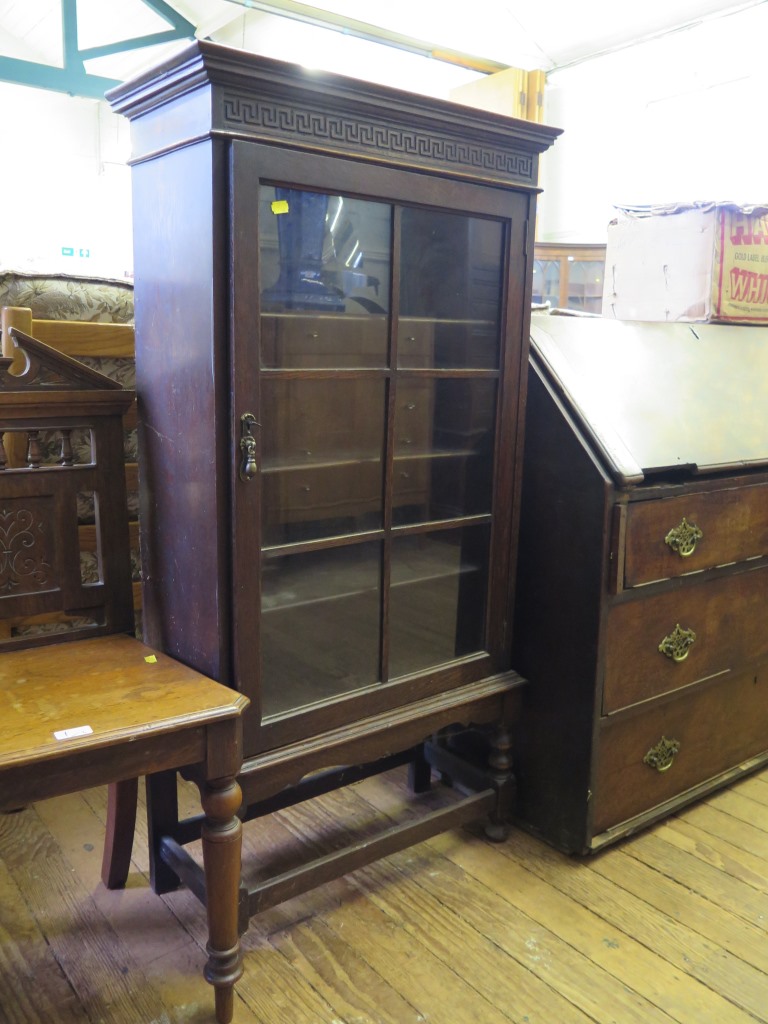 An oak bookcase, with Greek key frieze, glazed door and turned legs, 62cm wide 121cm high