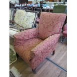 An Edwardian upholstered armchair, the rectangular back and scroll arms on turned legs and castors