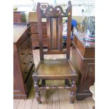 An early 18th century elm chair, the panelled back with fret carved scroll top rail over a solid