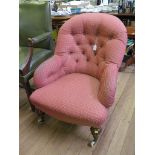 An Edwardian button back lady's armchair on turned oak legs and pot castors