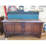 An 18th century oak coffer, the single panelled lid over a four panel front on scroll carved